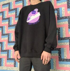 Person wearing a black sweatshirt with logo artwork on chest.
